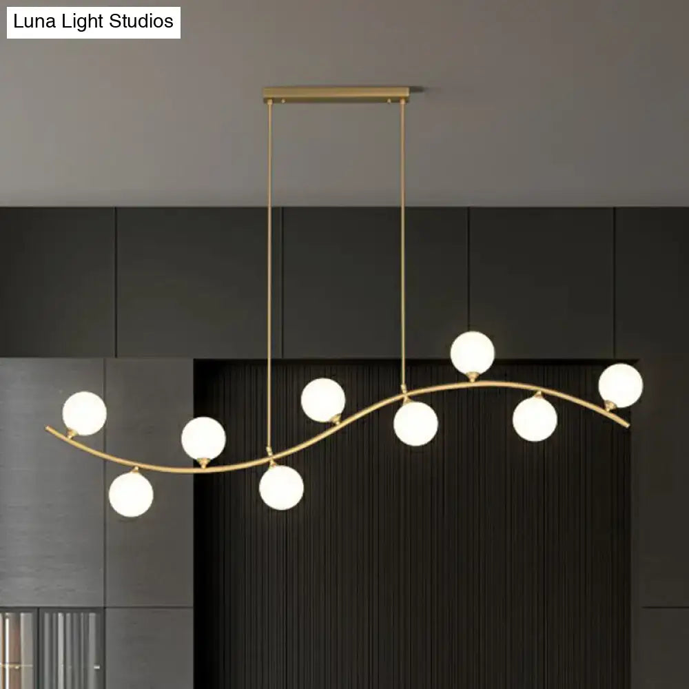 Gold-toned DecorBites pendant lighting with a wavy ceiling pendant design featuring seven milk ball glass bulbs for minimalist spaces