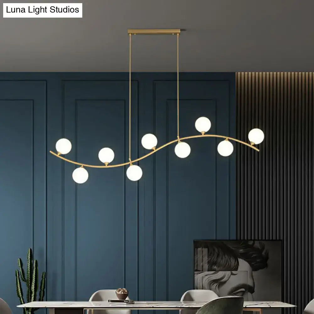Gold-toned DecorBites minimalist wavy ceiling pendant with seven white milk ball glass bulbs for dining room island lighting