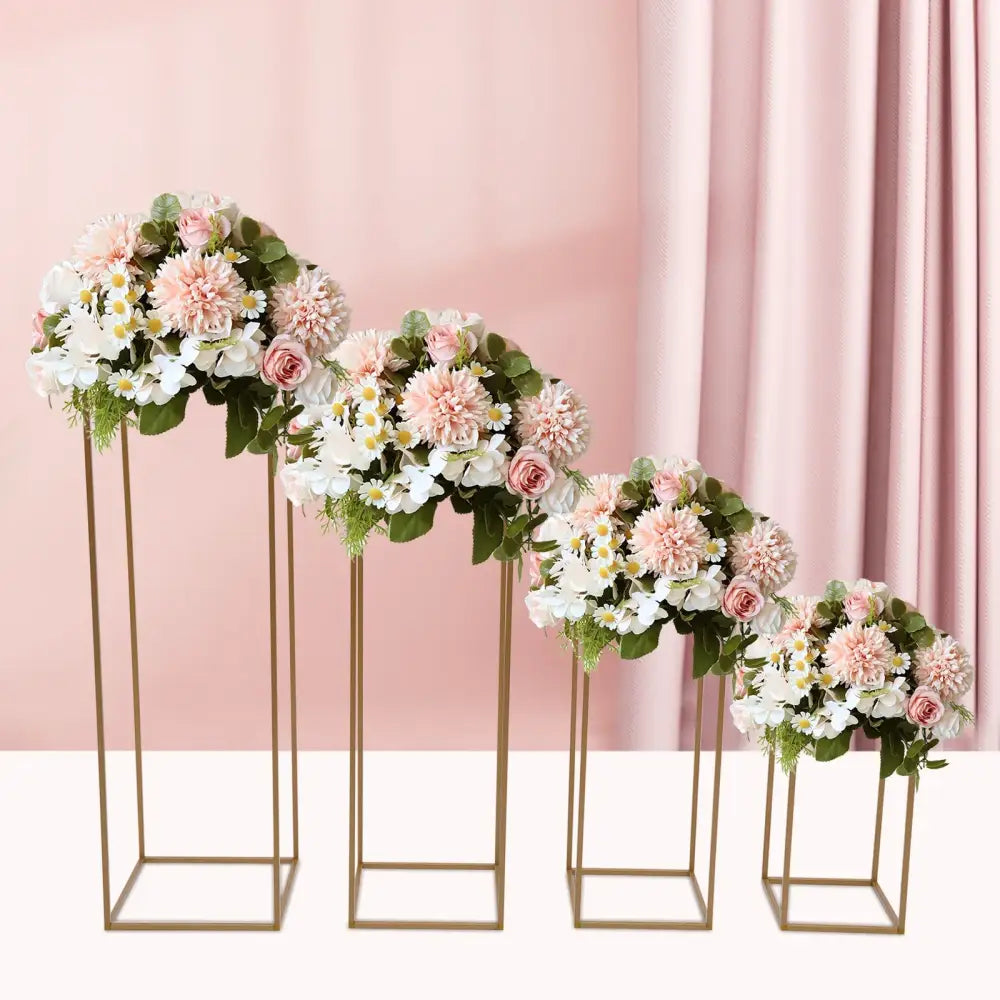 A set of four gold-toned metal flower vase stands with pink and white artificial flowers for gold wedding decor