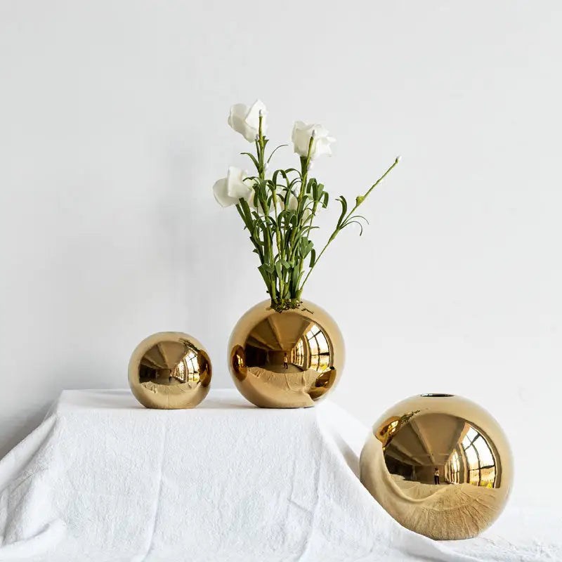Decorbites golden ball ceramic vases in shiny gold with varying sizes and one holding white flowers for home decor