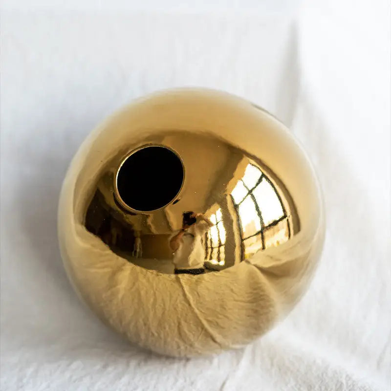 DecorBites™ golden ball ceramic vase with a shiny gold spherical smooth reflective surface for home decor