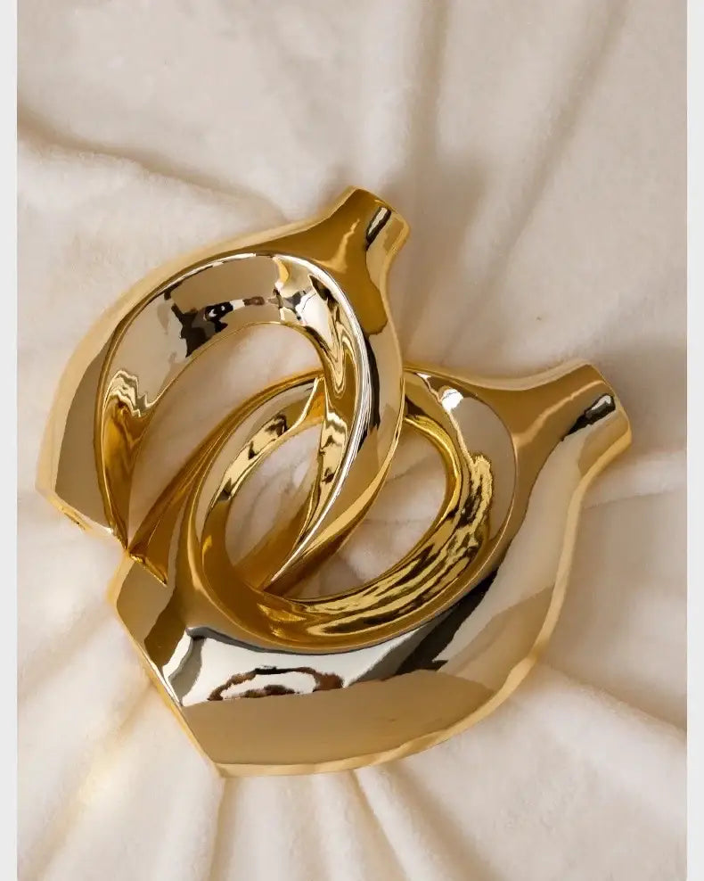 Decorbites golden flower vase featuring a golden metallic abstract sculpture with intertwined ring-like forms