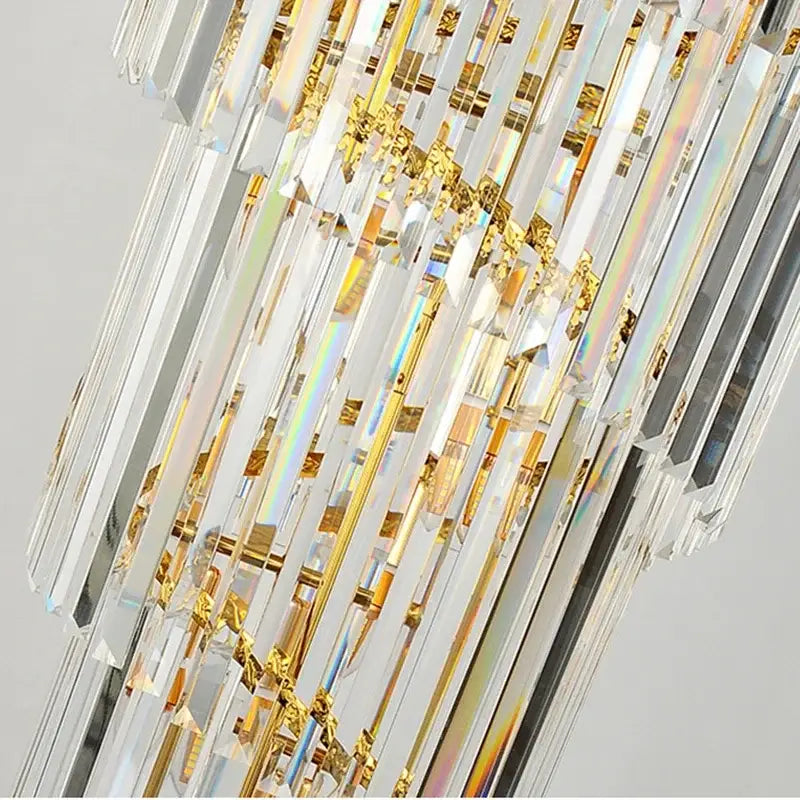 A modern decorbites golden luxury chandelier with cascading clear crystal prisms for luxury hotel lobby use