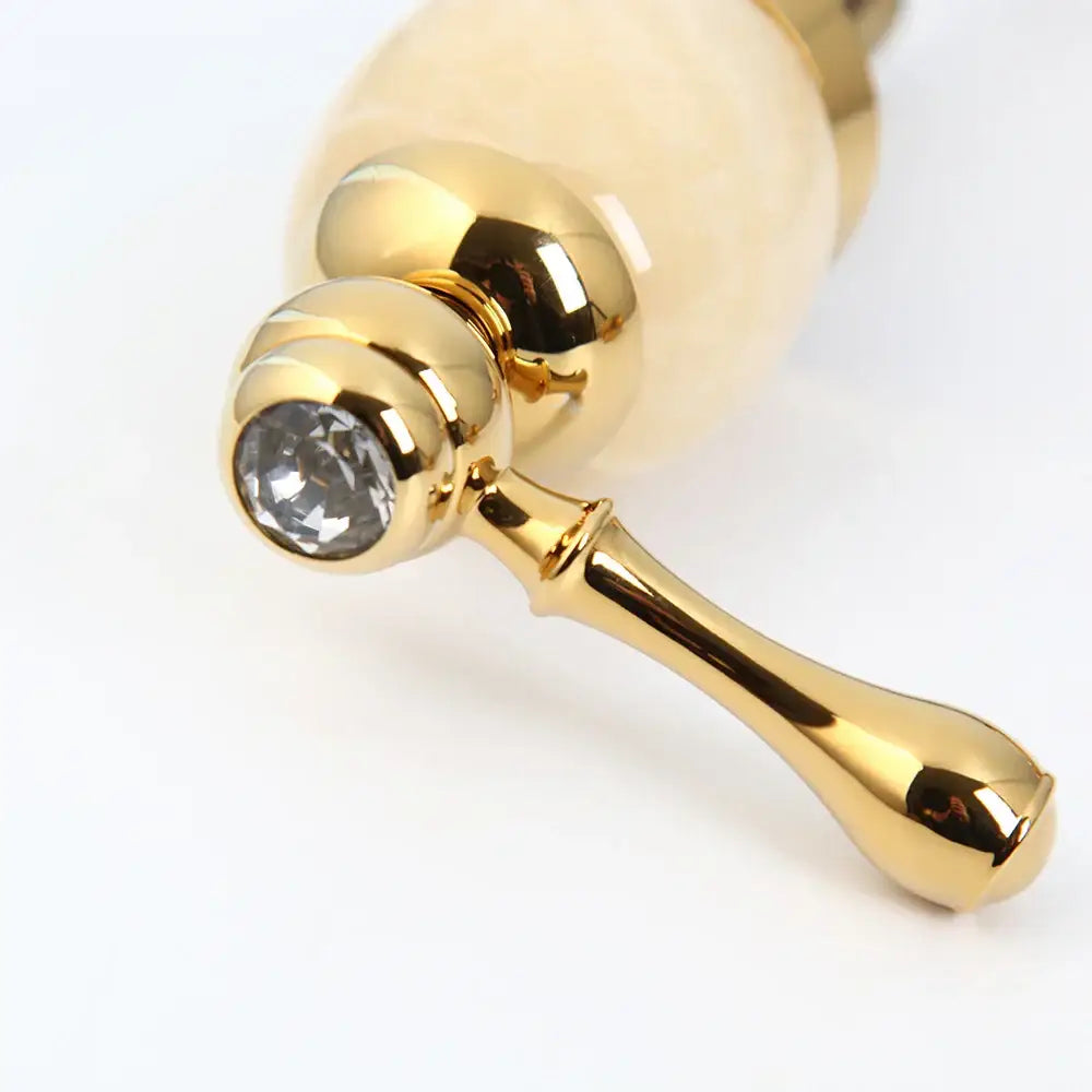 Decorbites golden plated waterfall bathtub faucet with gold finish, faceted crystal accent, and off-white ceramic handles