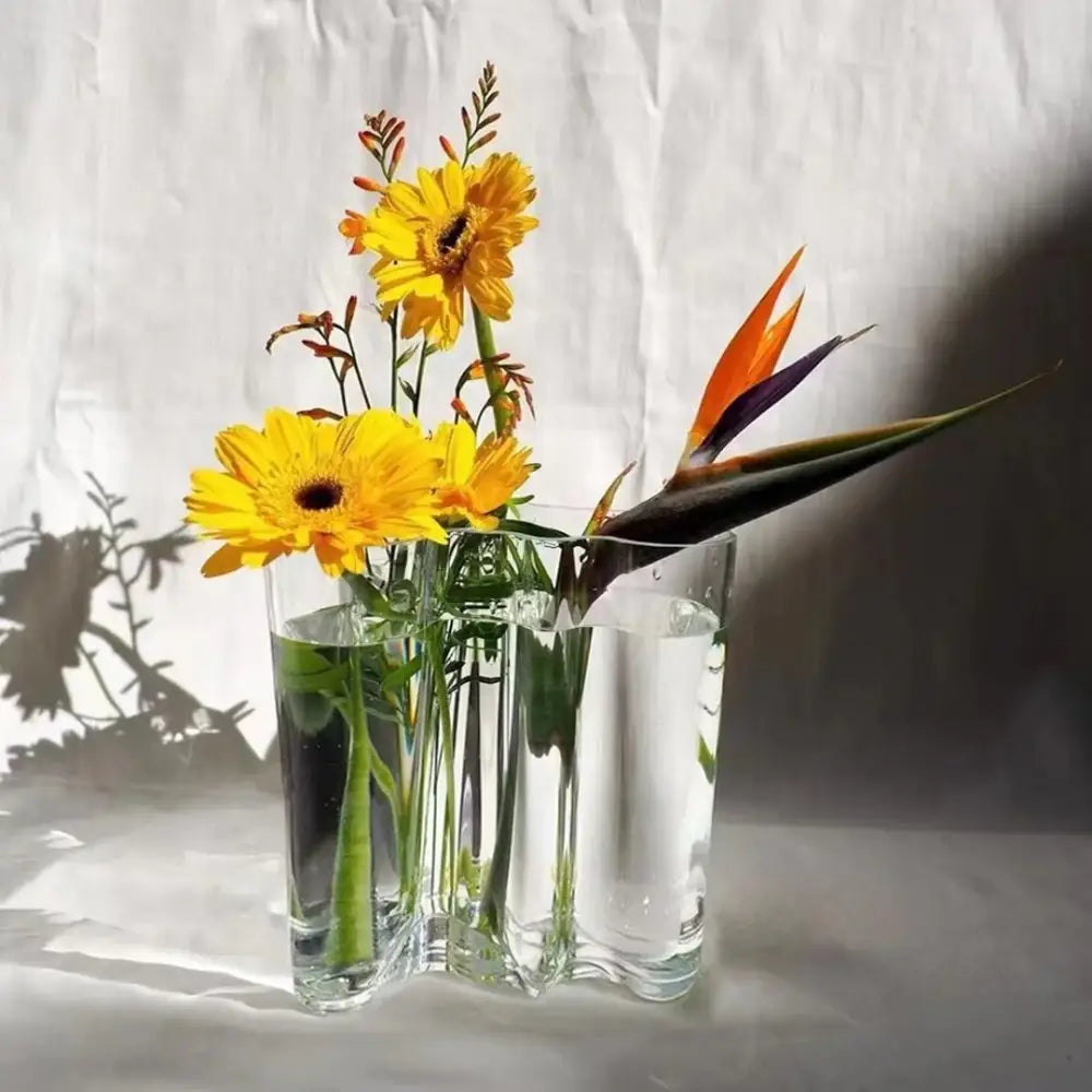 Decorbites™ green glass vase with modern wavy design holding yellow gerbera daisies and orange bird of paradise flower