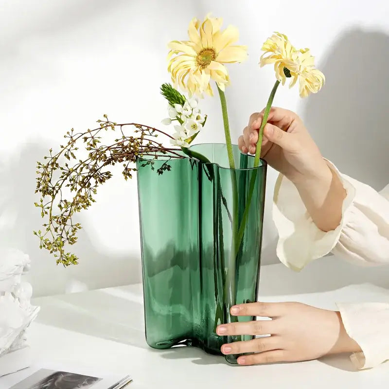 Decorbites™ green glass vase with a sleek wavy design holding yellow and white flowers for modern decor