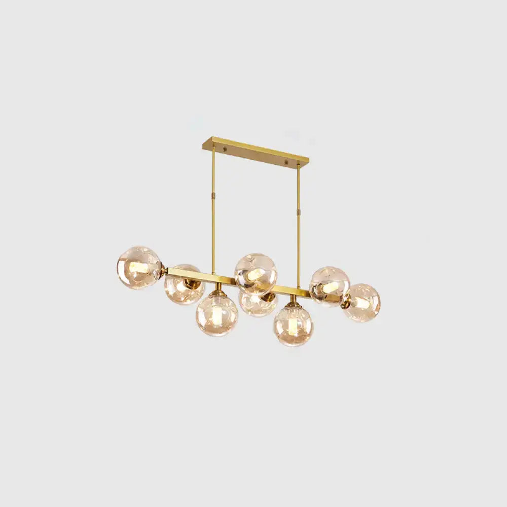 Gold-toned DecorBites™ modern chandelier with seven hand-blown dimpled glass amber bulbs for restaurant island lighting