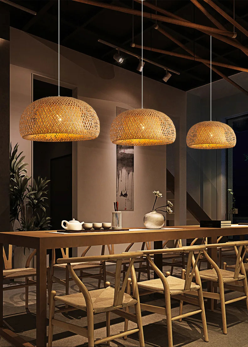 Three warm-toned hand-woven bamboo pendant light chandeliers hang above a wooden dining table in a decorbites pendant light chandelier design