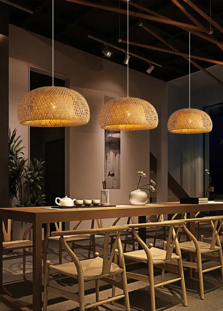 Three warm-toned hand-woven bamboo pendant light chandeliers hang above a wooden dining table in a decorbites pendant light chandelier design