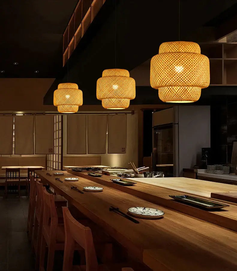 Warm tiered pendant light chandelier with hand-woven bamboo shades above wooden dining counter by decorbites