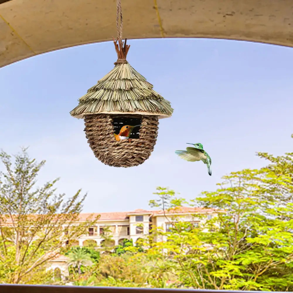A rustic thatched-roof nest house crafted from woven natural fibers hung by rope as a charming decorative hummingbird house