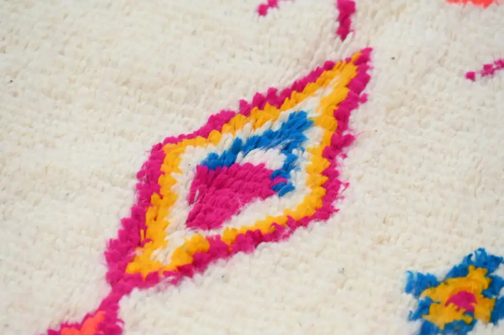 Vibrant handcrafted moroccan azilal rug with bold pink yellow and blue geometric diamond pattern on cream background