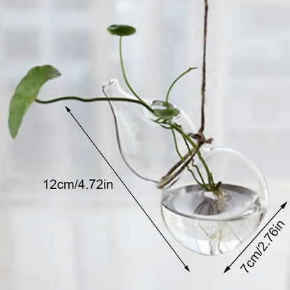 Clear glass hanging DecorBites™ angel vase with teapot top and spherical base holding green plant stems