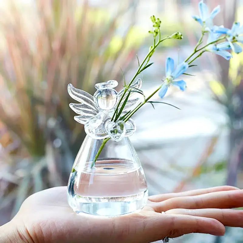 Clear glass angel-shaped vase by DecorBites holding delicate blue flowers for elegant home decor