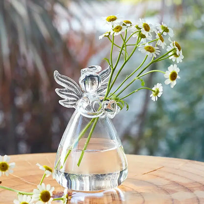 Clear glass angel shaped vase by DecorBites™ holding white daisies with yellow centers for home decor