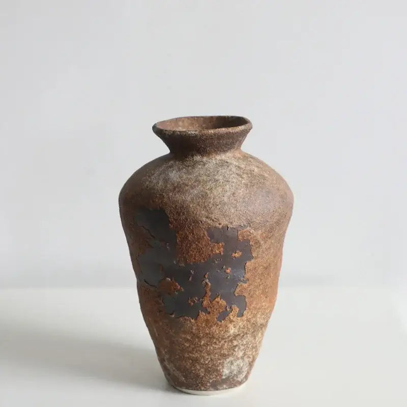 Earthy brown handmade ceramic vase with a textured rustic surface and dark glaze patches for zen flower arrangements