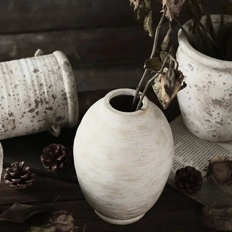 A rustic white handmade ceramic vase with a speckled weathered finish and oval shape from decorbites vintage style
