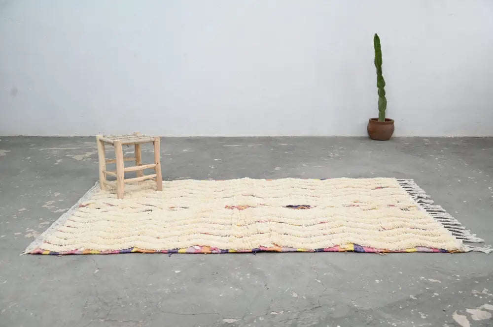 Cream-colored handmade moroccan azilal rug with textured wave pattern and multicolored fringe 223x133 cm