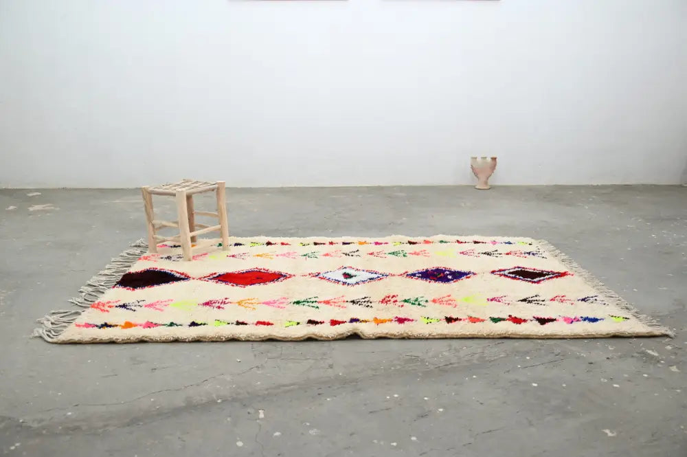Cream-colored handmade moroccan azilal rug with vibrant geometric patterns on textured wool base 231x152 cm