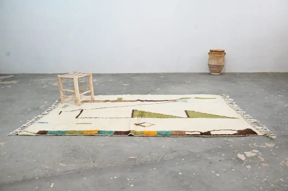 Cream-colored wool handmade traditional azilal rug with green brown and teal geometric patterns moroccan handmade decorbites