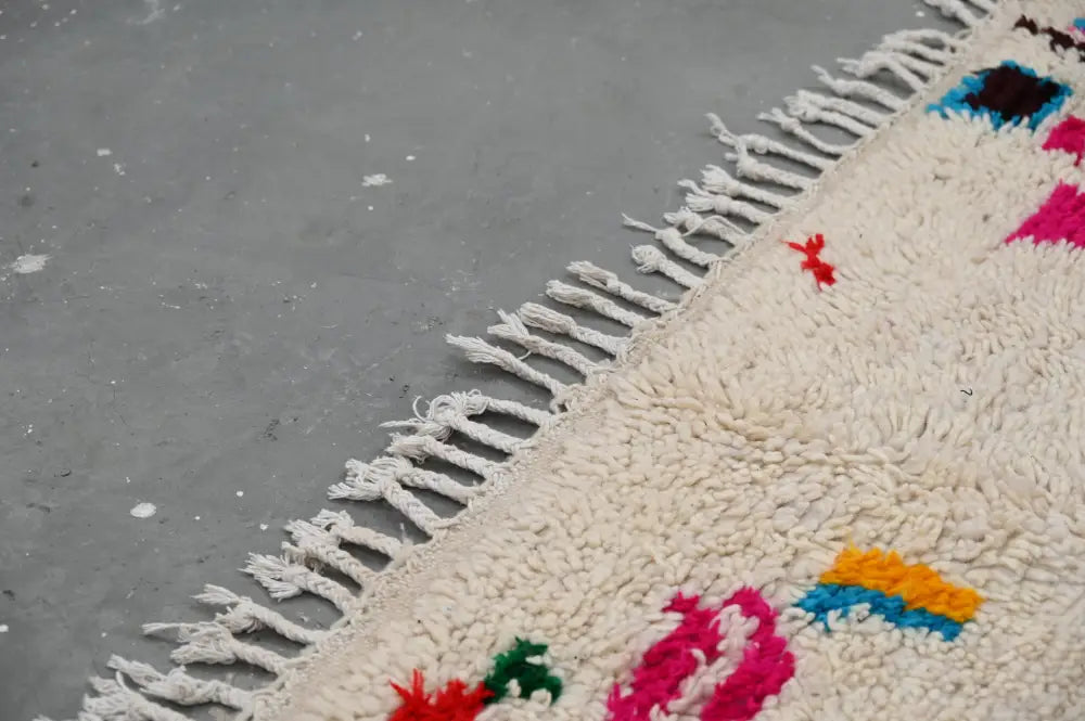 Cream-colored decorbites™ handmade moroccan azilal rug 240x132cm with vibrant geometric patterns and thick fringe edge