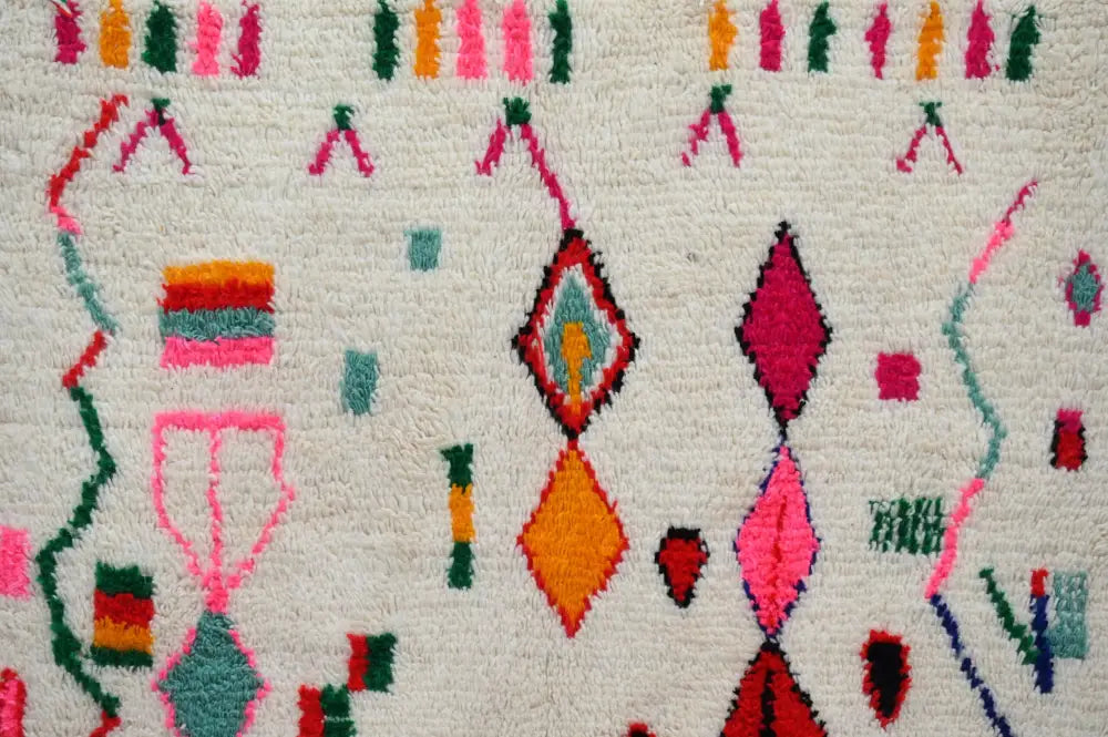 DecorBites™ handmade traditional azilal rug with vibrant pink, orange, green, and red geometric motifs on white base