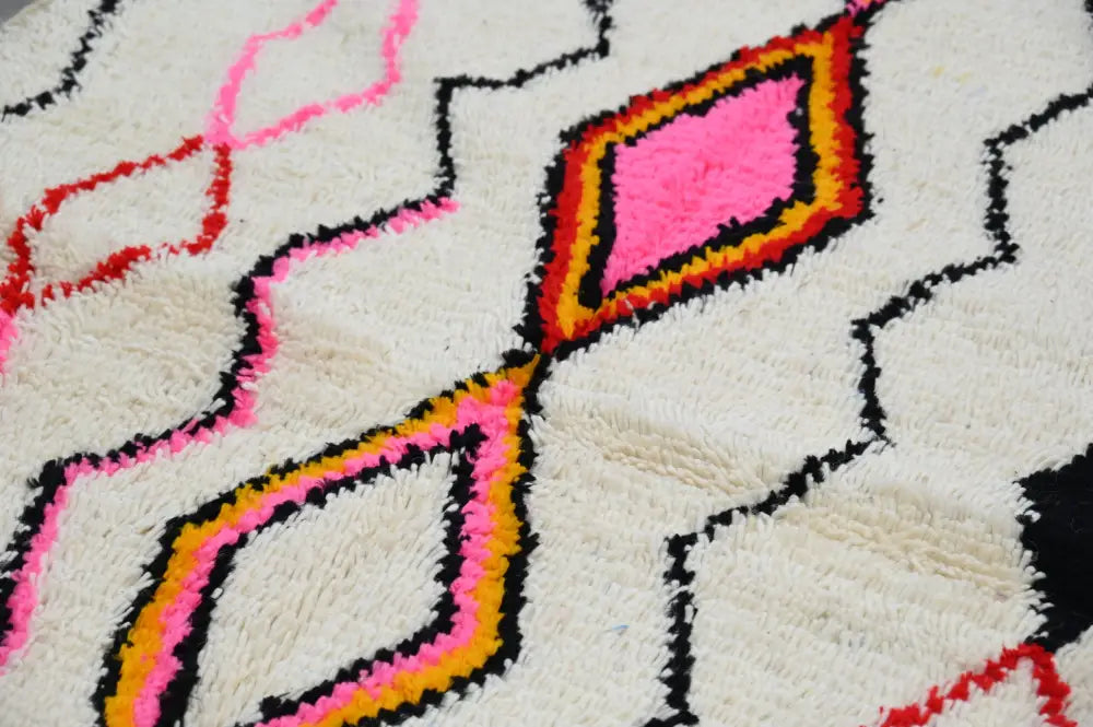 A plush white decorbites™ handmade azilal rug 240x150cm with bold pink orange and black geometric patterns in natural wool