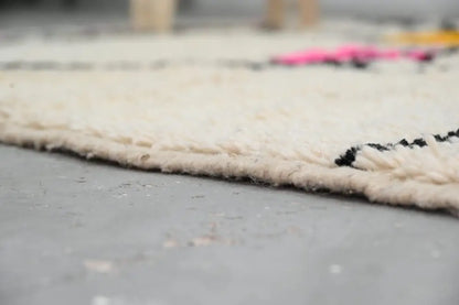 Cream-colored thickly woven wool moroccan azilal rug with textured fringe and bold black geometric patterns 240x152 cm