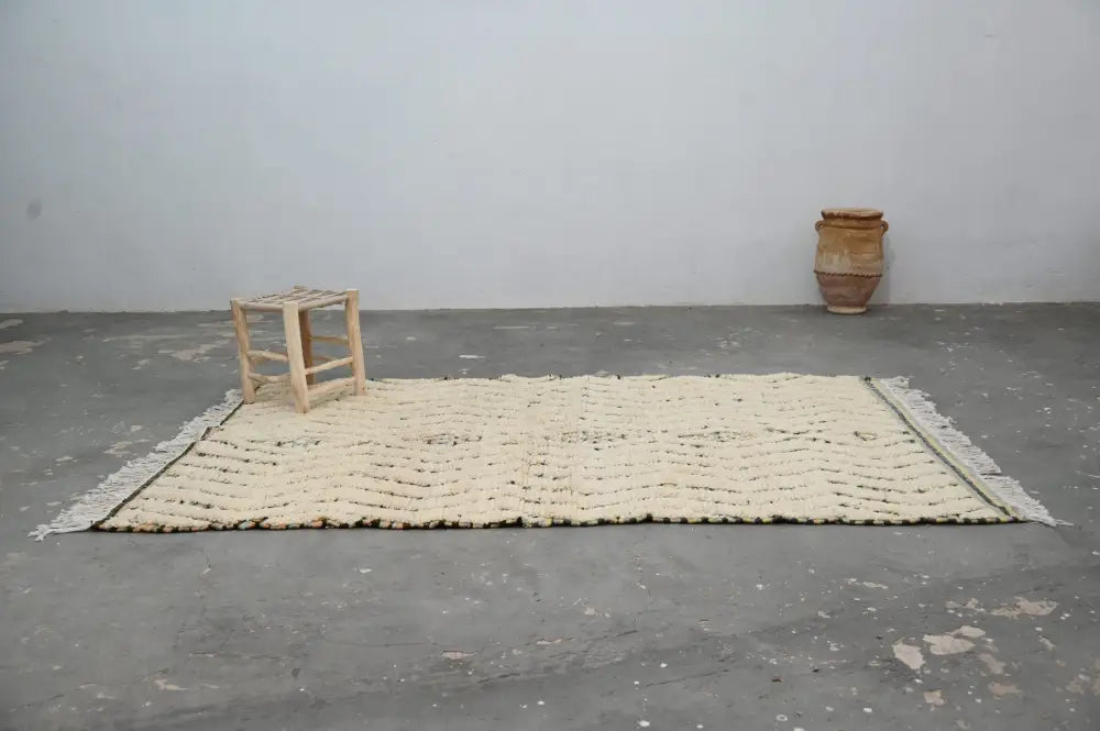 Cream-colored handmade moroccan azilal rug 240x155cm with textured chevron pattern and fringed edges by decorbites