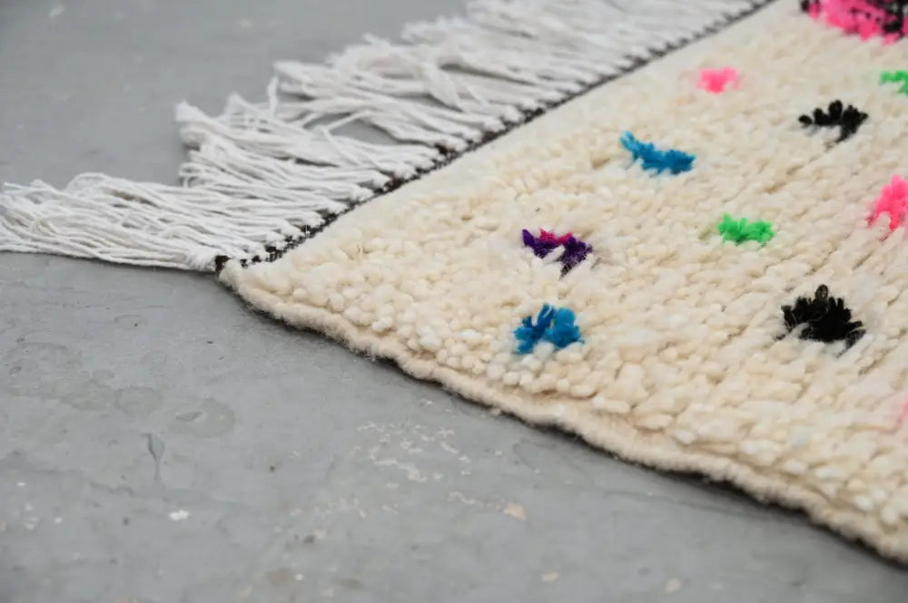 Cream-colored decorbites™ handmade traditional azilal rug with colorful embroidered dots and white fringe 241x140 cm