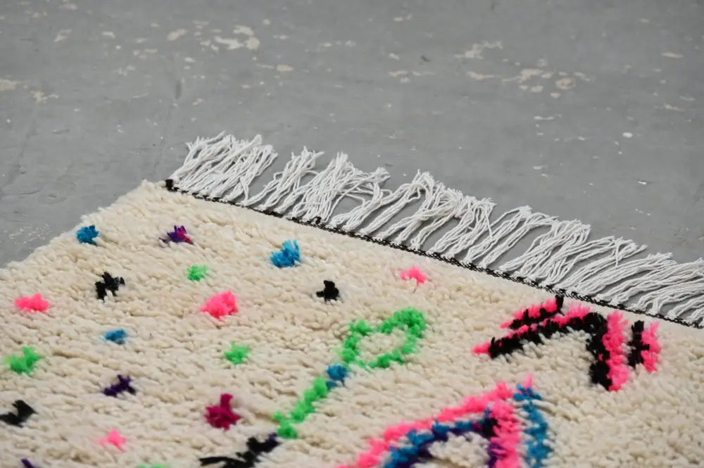Cream-colored handmade traditional azilal rug with vibrant neon geometric patterns and white fringe 241x140 cm decorbites