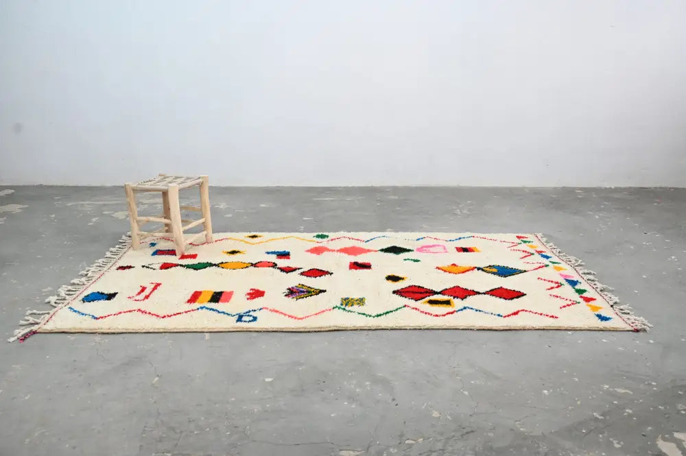 Cream-colored decorbites™ handmade traditional azilal rug with vibrant geometric patterns on textured wool base