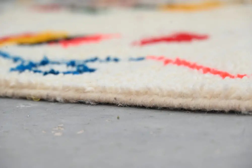 Cream-colored wool handmade traditional azilal rug with vibrant red blue and yellow geometric patterns 242x140cm