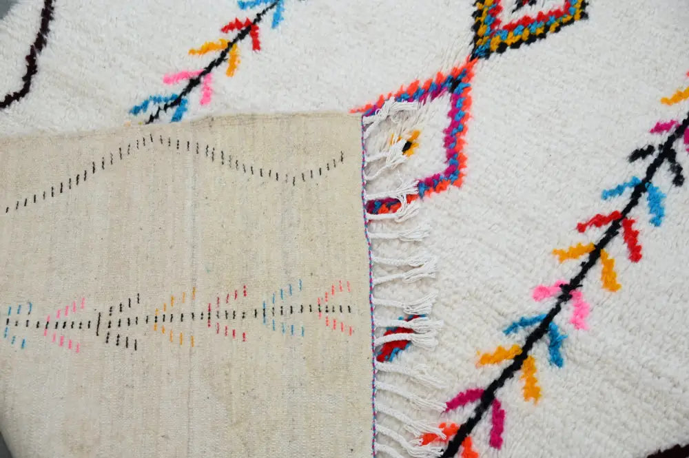 Handwoven decorbites™ handmade moroccan azilal rug with white base and vibrant black red blue pink yellow geometric patterns