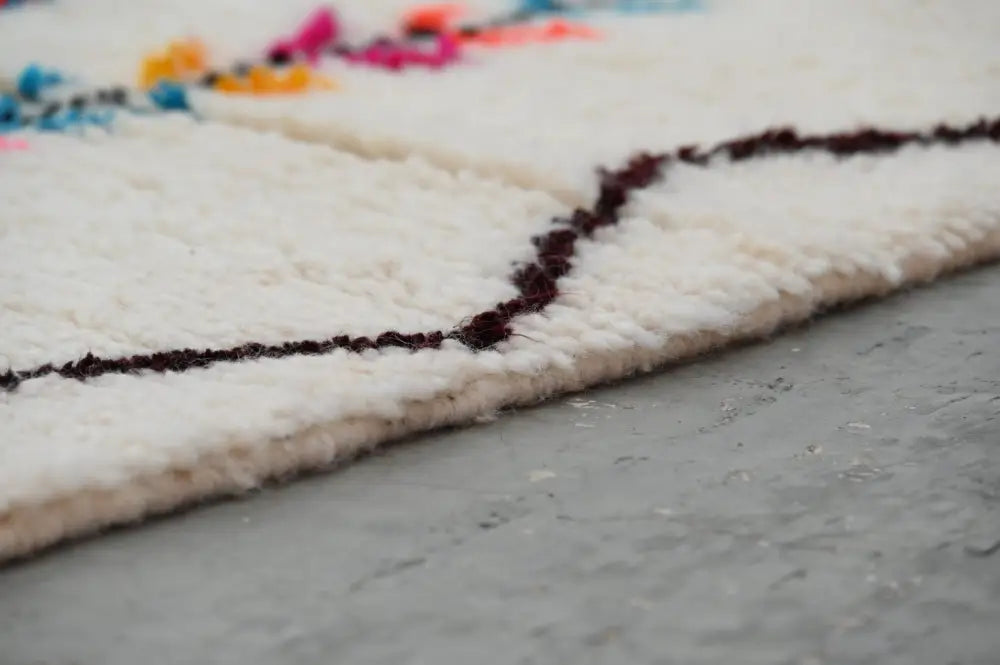 White woolen decorbites™ handmade moroccan azilal rug with fluffy texture and bold dark burgundy geometric borders