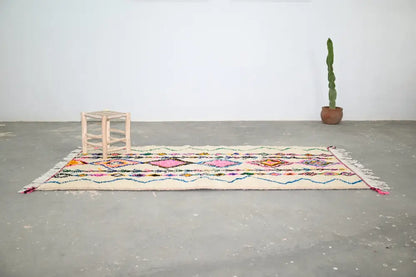 Beige handmade moroccan azilal rug with vibrant pink orange and blue geometric patterns 243x131 cm by decorbites