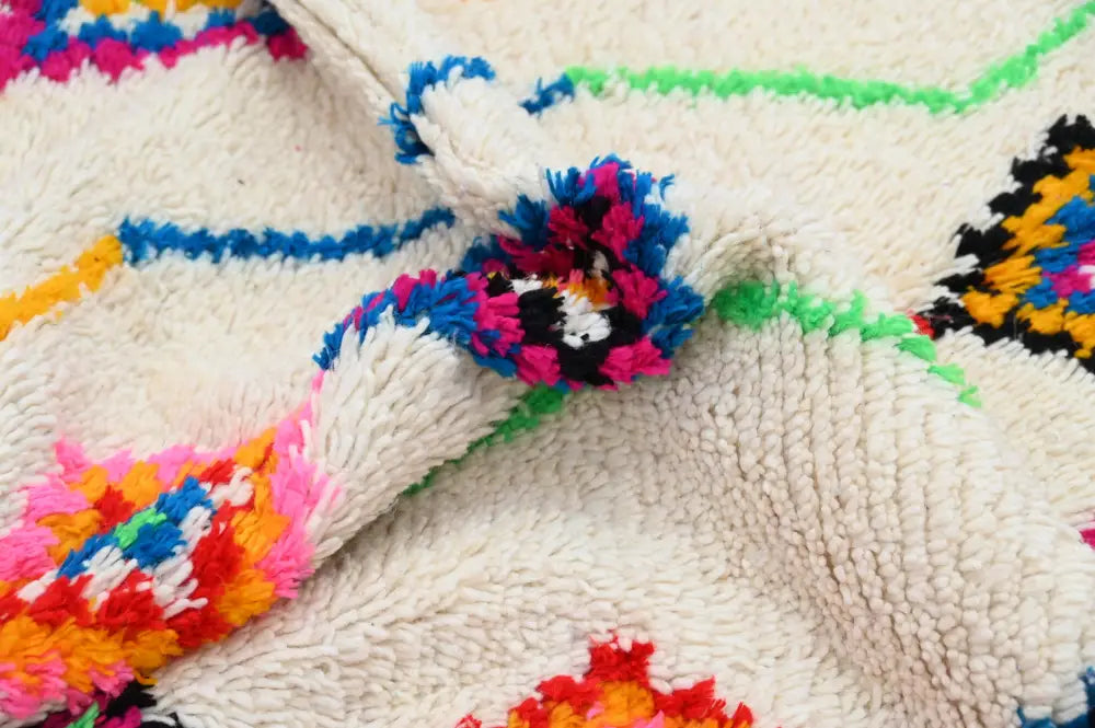 Cream-colored decorbites™ handmade moroccan azilal rug with vibrant geometric patterns and fluffy tassels 246x142cm