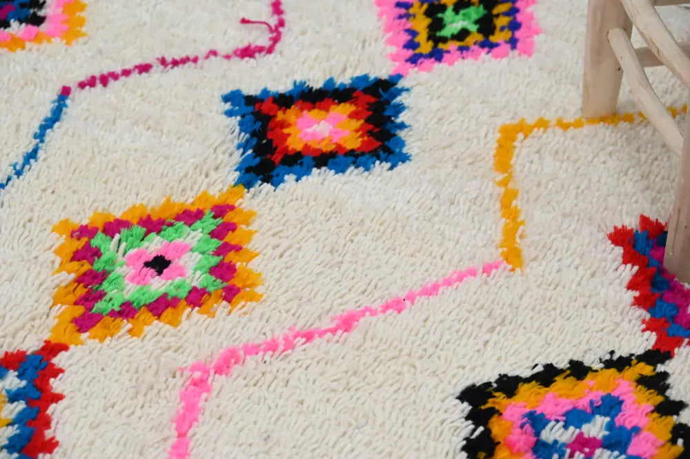 A vibrant moroccan handmade azilal rug with fluffy white texture and colorful traditional geometric patterns by DecorBites