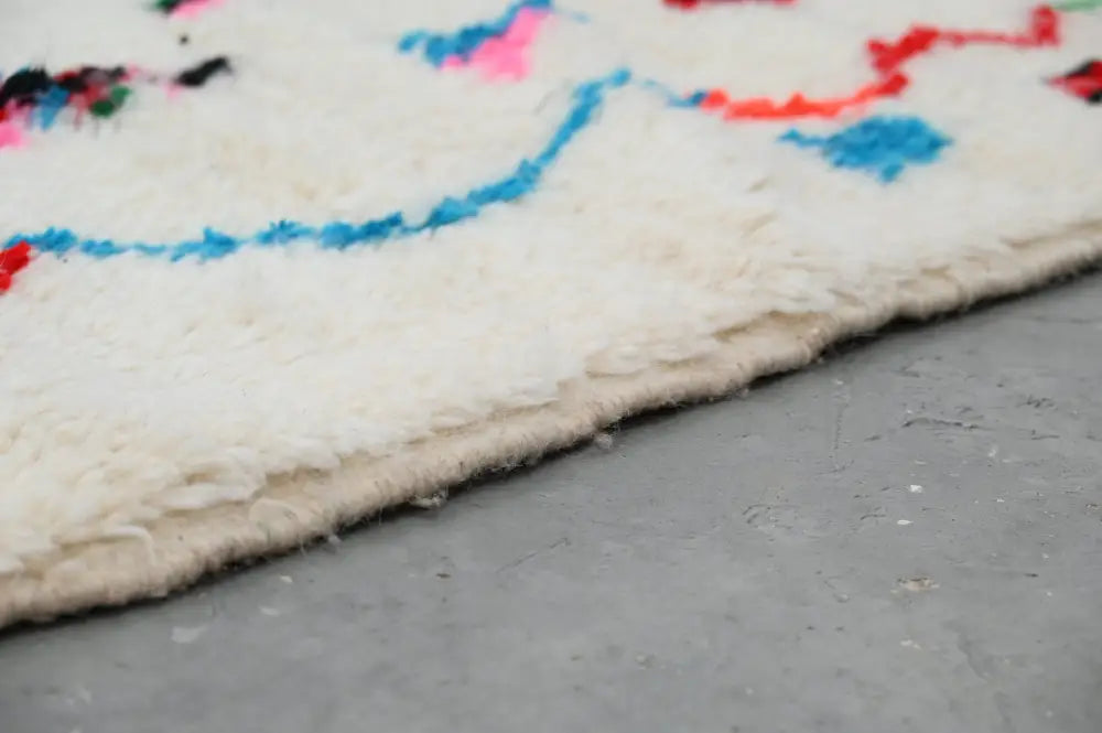 DecorBites™ handmade moroccan azilal rug 247x141 cm with fluffy off-white base and vibrant blue red pink geometric patterns