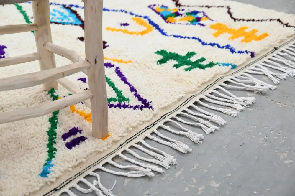Cream-colored handmade moroccan azilal rug with vibrant blue green yellow purple geometric patterns and fringe edge 250x141 cm