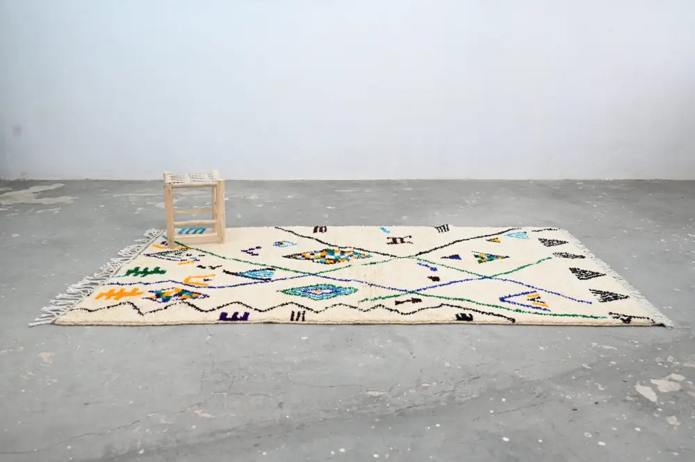 Cream-colored handmade Moroccan Azilal rug with intricate black blue green and orange geometric patterns 250x141 cm