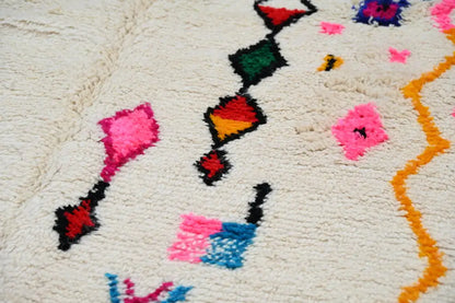A plush off-white handmade moroccan azilal rug with vibrant geometric patterns in pink red green blue and orange 250x145 cm