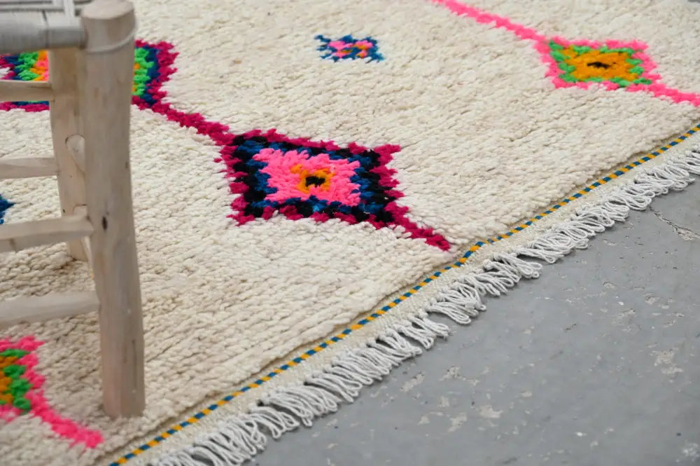 Cream-colored handmade moroccan azilal rug with vibrant pink green and blue geometric patterns and white fringe 250x148 cm