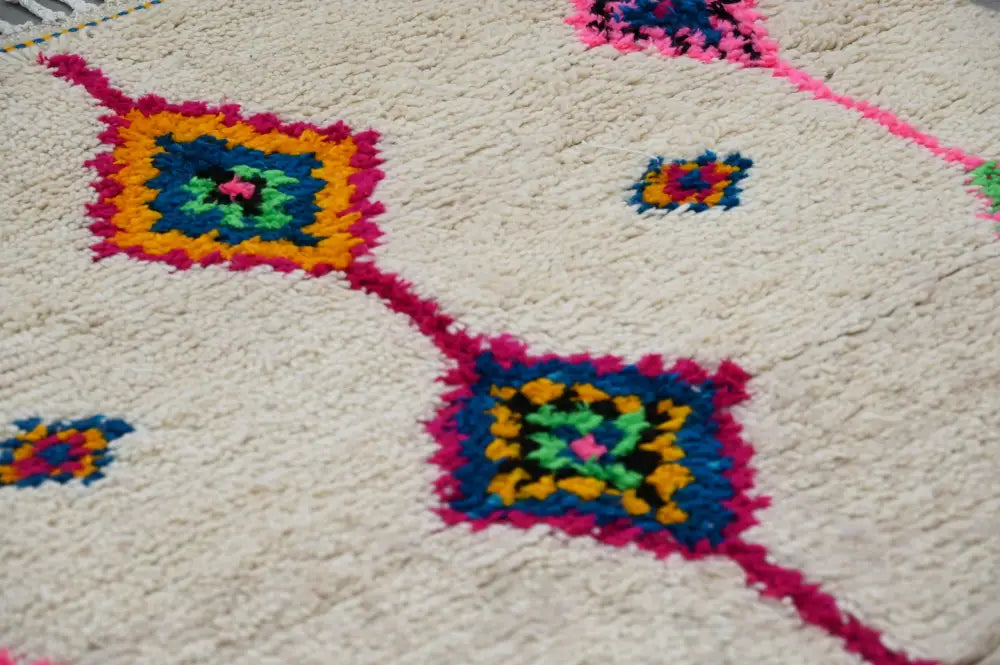 Cream-colored handmade moroccan azilal rug with vibrant pink orange blue green and yellow geometric patterns 250x148 cm
