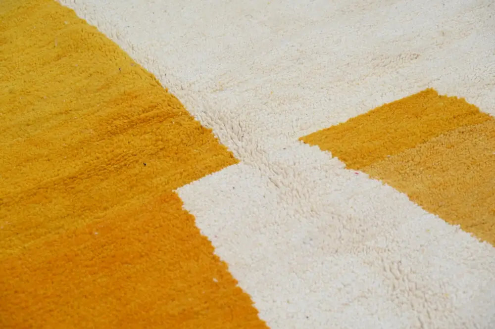 A plush handmade traditional azilal rug by decorbites in mustard yellow and off-white with bold geometric patterns
