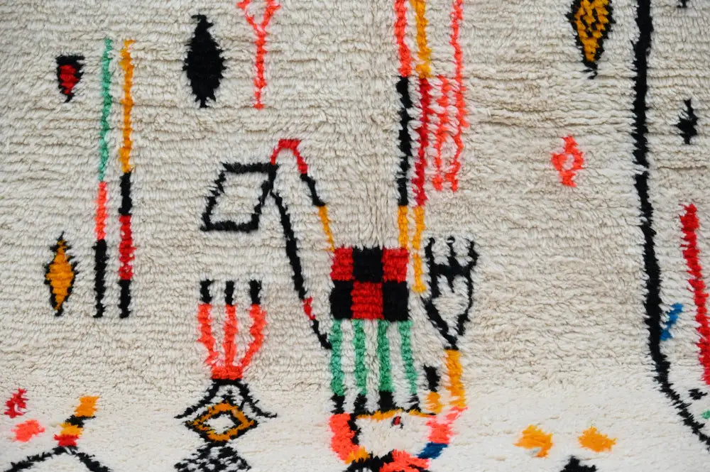 Cream-colored textured decorbites™ handmade moroccan azilal rug with vibrant geometric pattern and bold red black accents