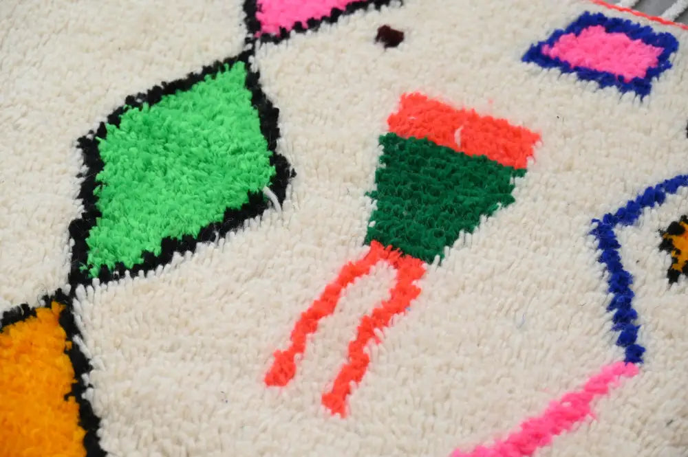 A cream-colored azilal rug with bold green pink orange and blue geometric patterns made of natural wool 250x160cm