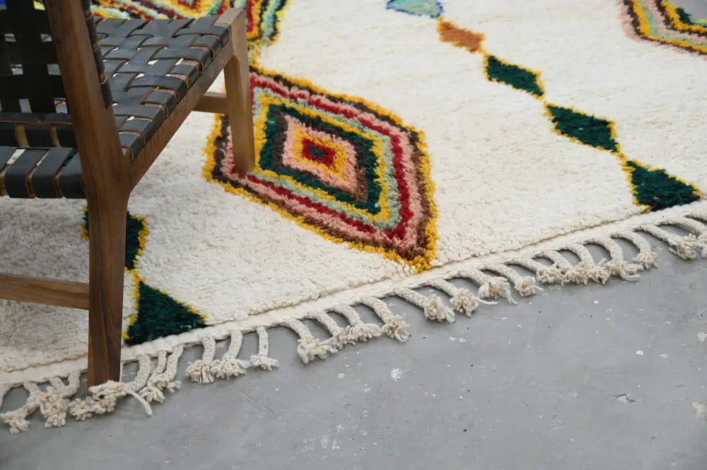 Cream-colored handmade moroccan azilal rug with vibrant geometric pattern in reds yellows greens and oranges 300 x 206 cm