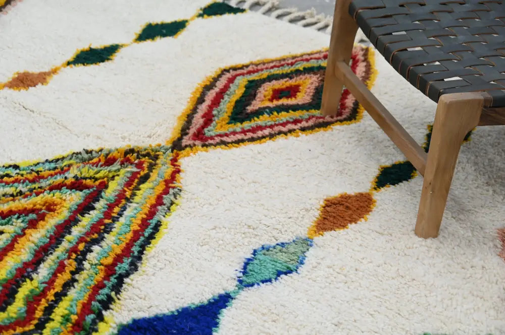 A vibrant handmade moroccan azilal rug with fluffy white texture and bold red green yellow blue and orange geometric patterns