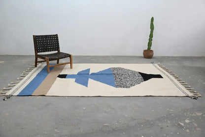Beige wool handmade traditional azilal rug with blue black gray geometric design and fringe edge moroccan craftsmanship
